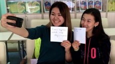 Girls taking a selfie with cell phone while holding up handwritten signs