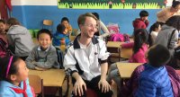 Ryan sits in the middle of young chinese children in a classroom