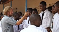 Male teacher gives fist bump to student in the middle of large group of students